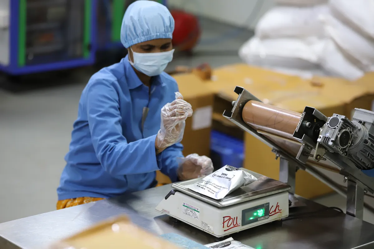 Worker packaging coffee pouches on packing line